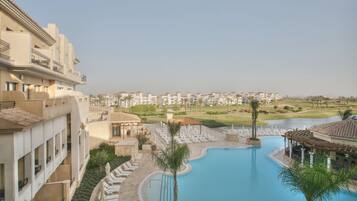 A resort with a swimming pool, lounge chairs, and a view of the surrounding landscape.