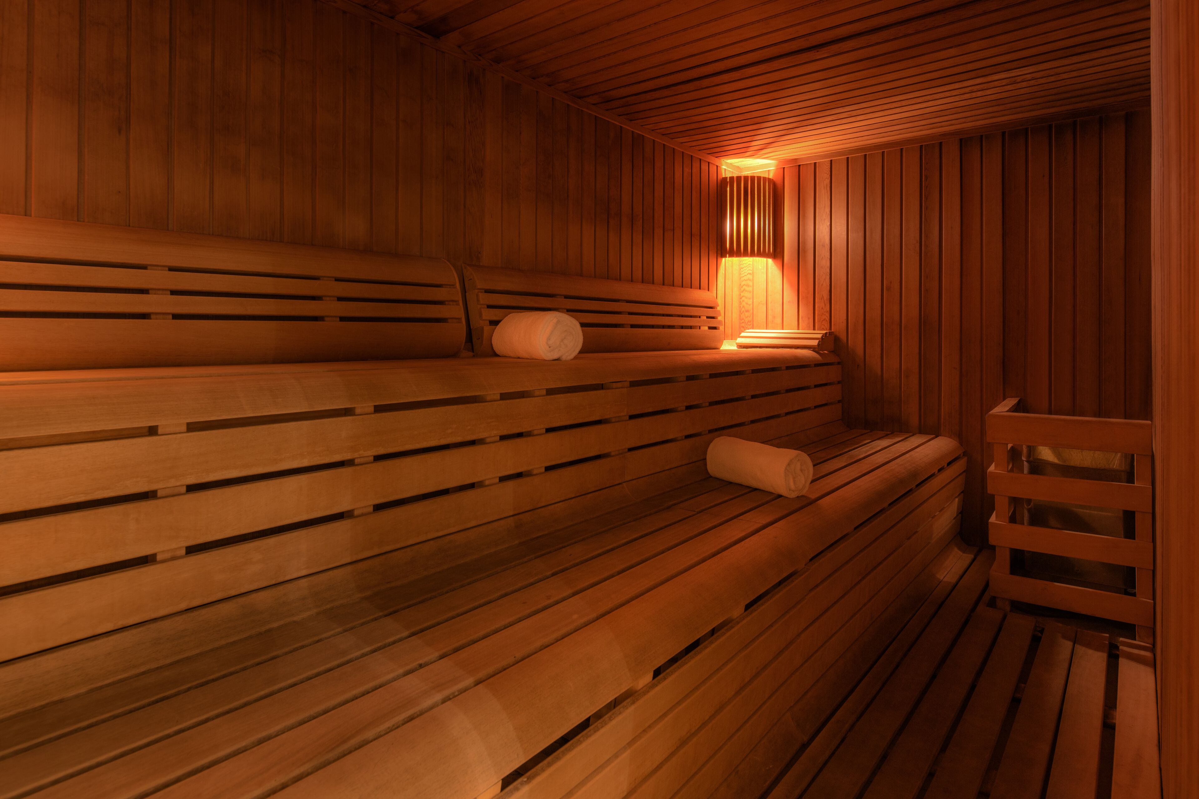 Una sauna de madera con bancos y un calentador fijado a la pared.