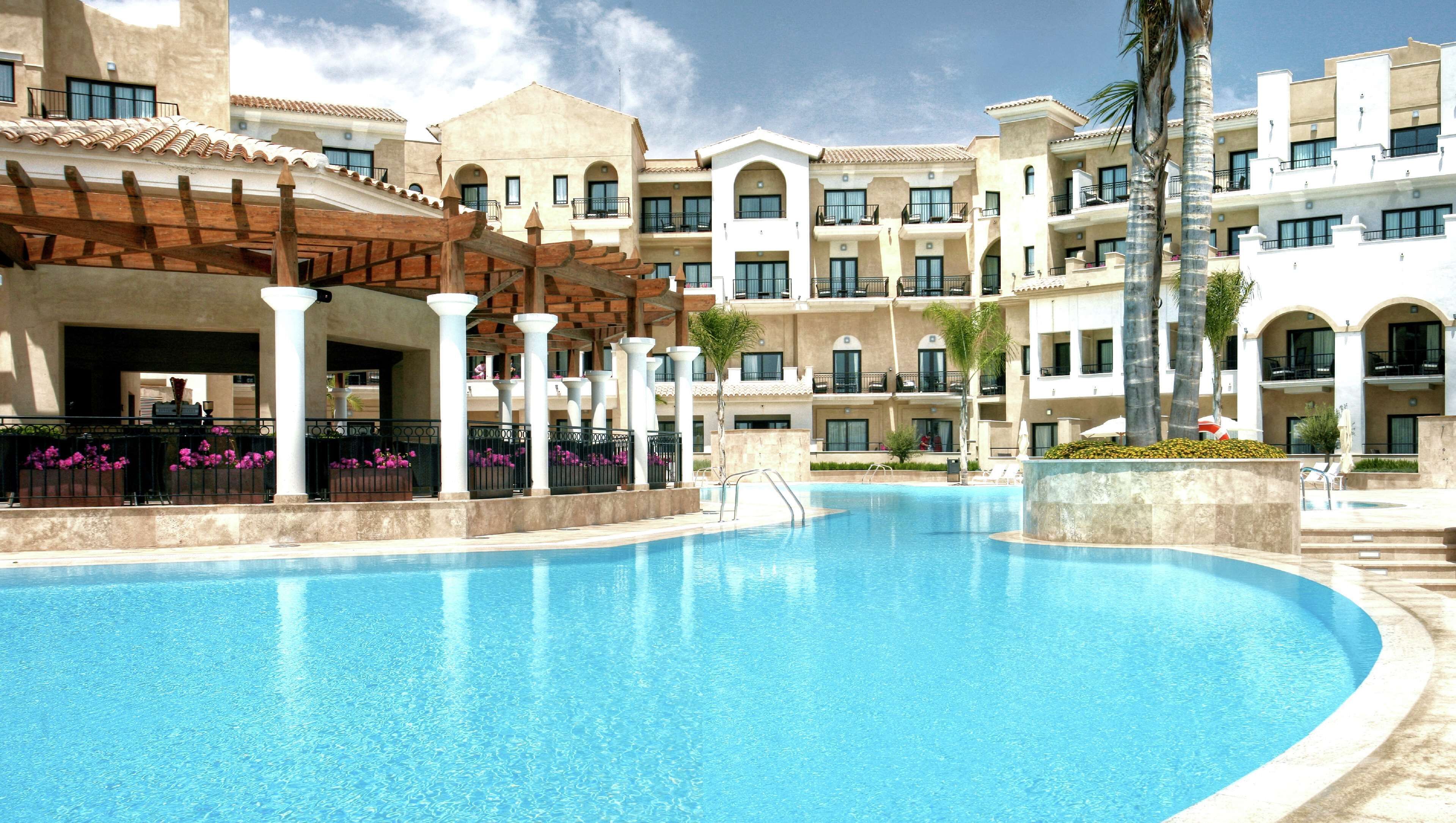 Ein Poolbereich eines Resorts mit einem großen Pool, mehreren Balkonen und einer überdachten Sitzgelegenheit.