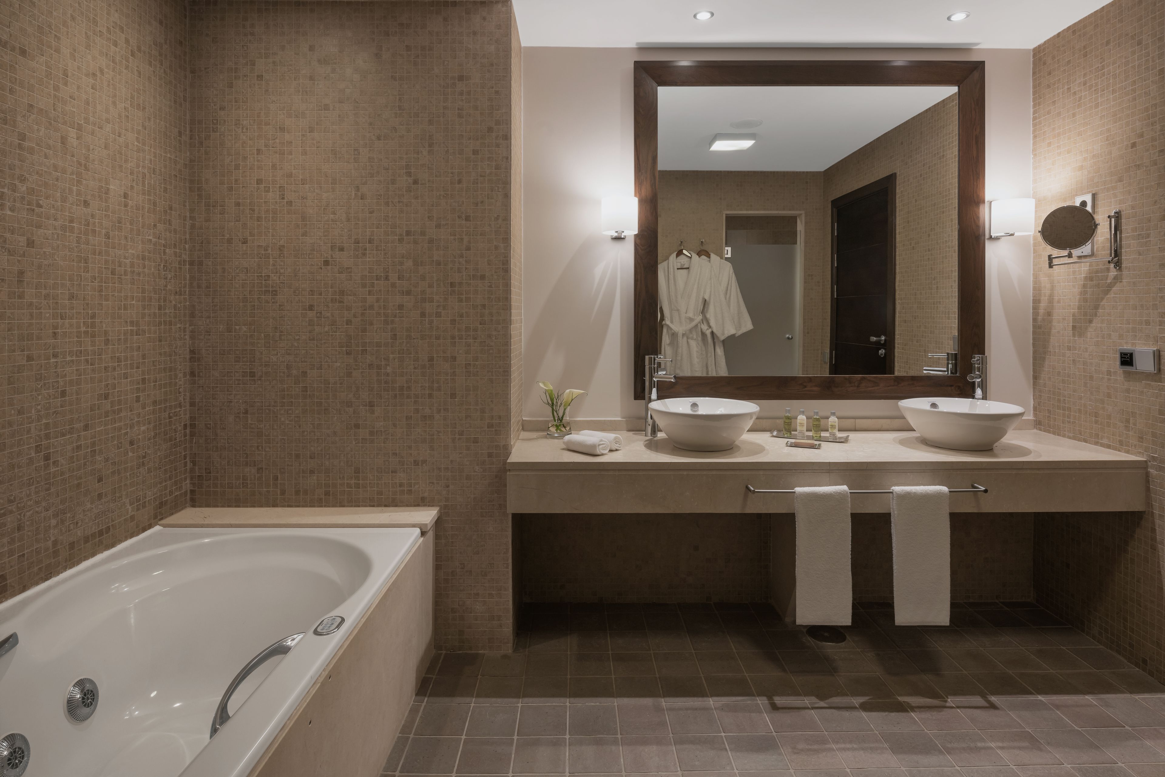 Un bagno moderno con una grande vasca, due lavandini e uno specchio sopra il mobile.
