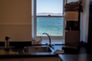 A kitchen with a window overlooking a body of water and distant land.