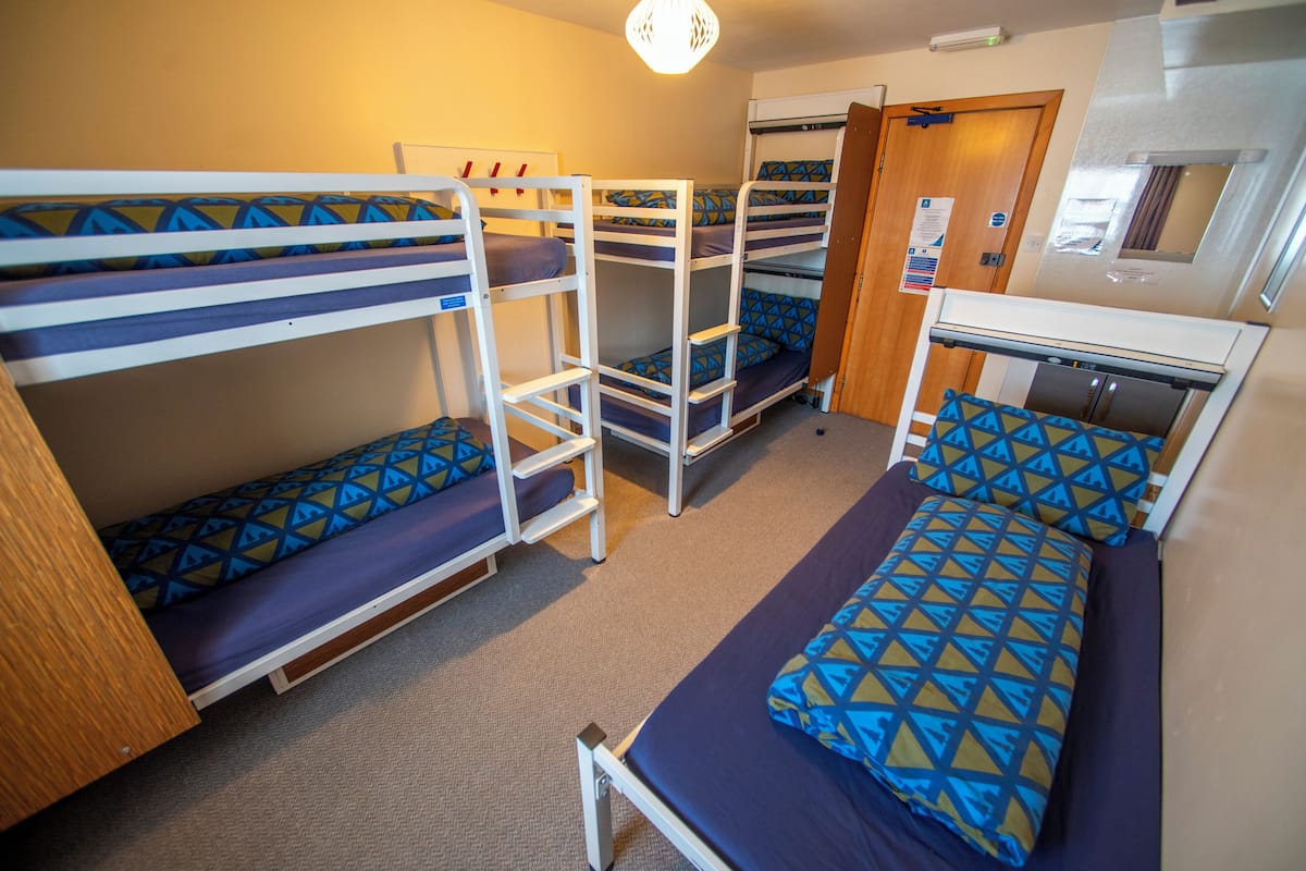 A bunk bed room with a kitchenette and a door to the outside.