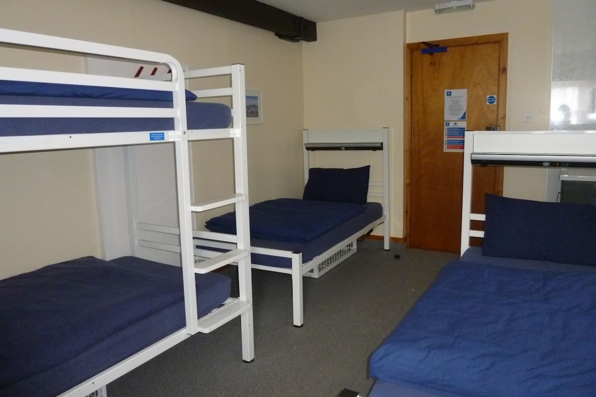 A room with bunk beds, a wooden door, and a white ceiling fan.