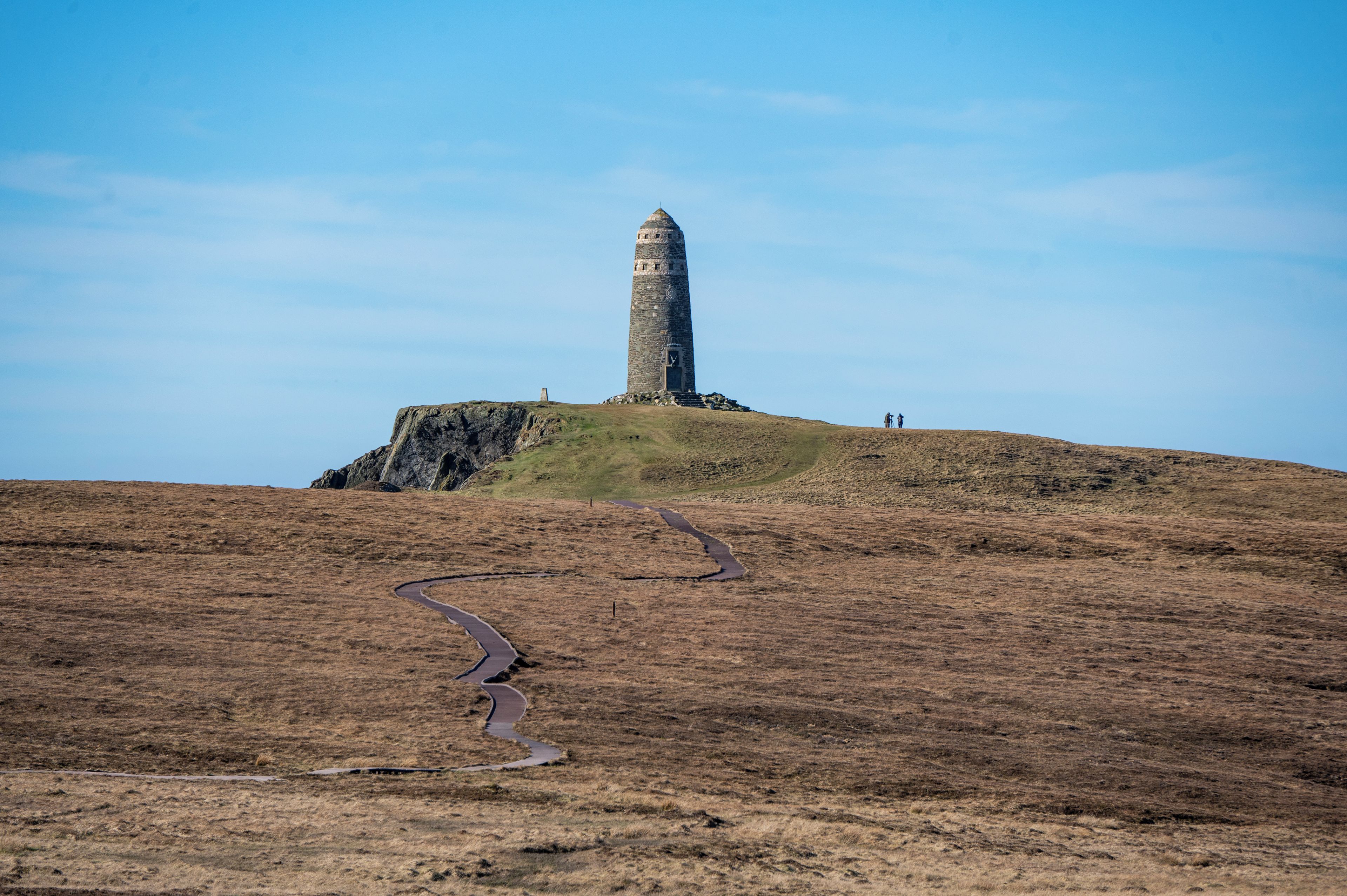 Una torre solitaria en una colina, con un camino serpenteante que lleva hacia ella.