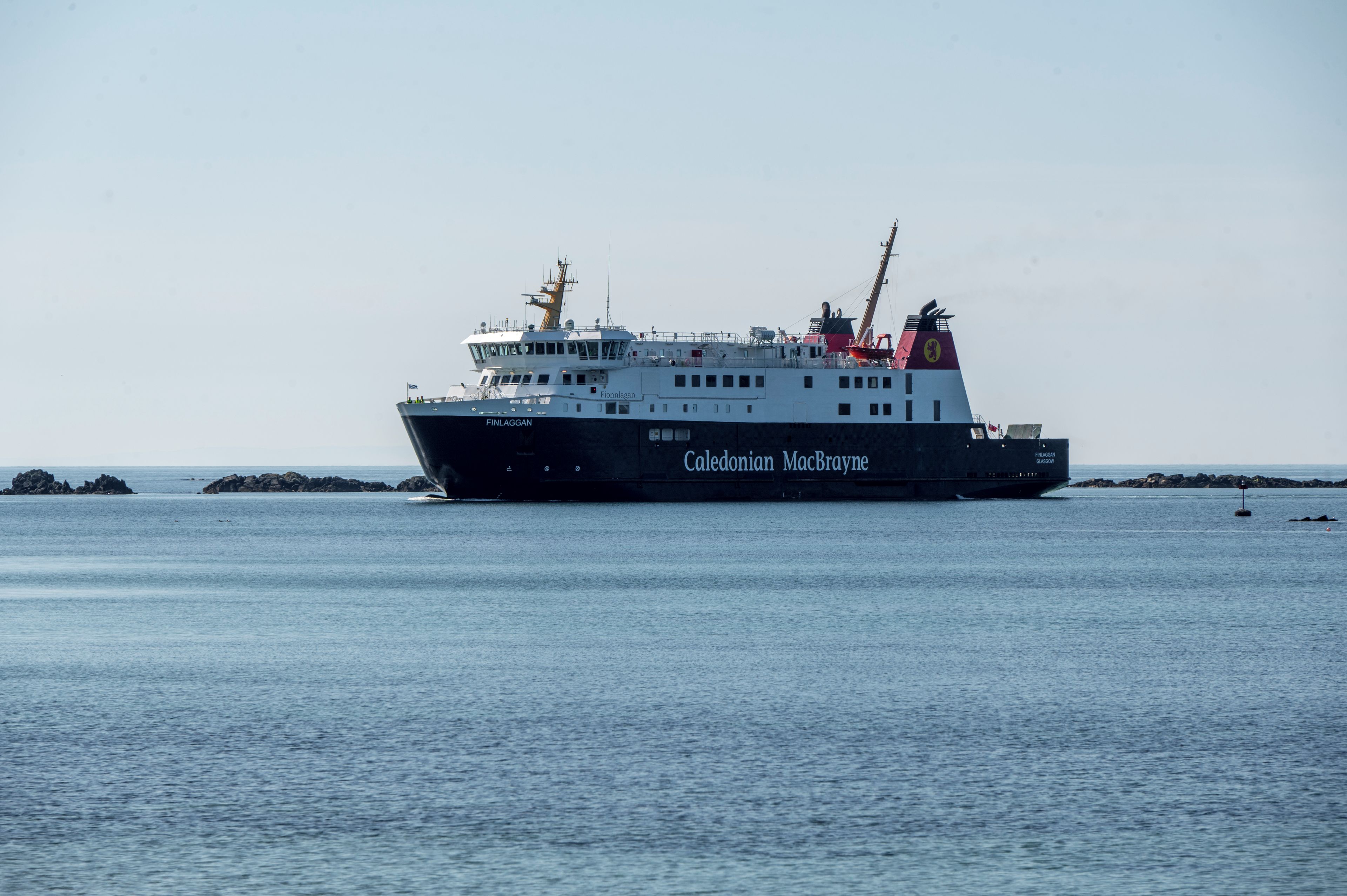 A large ship named 'Caledonian MacBride' with a black hull and white superstructure, sailing on calm waters.