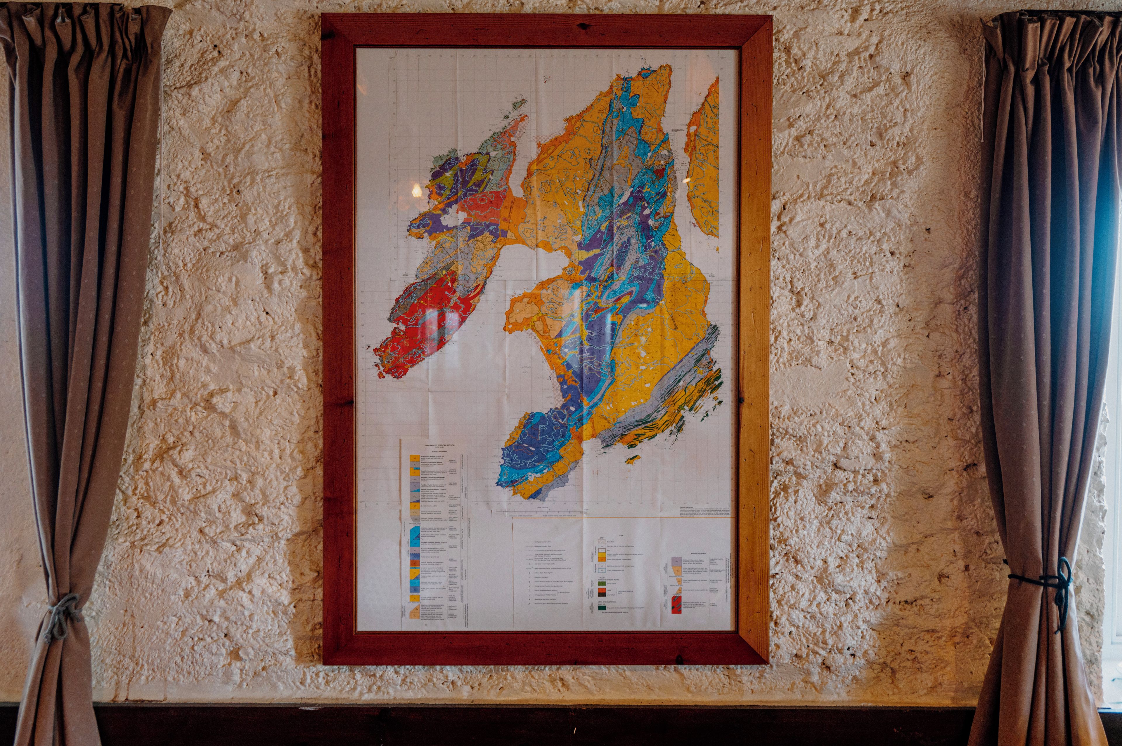 A framed geological map with a grid and legends, mounted on a textured wall.