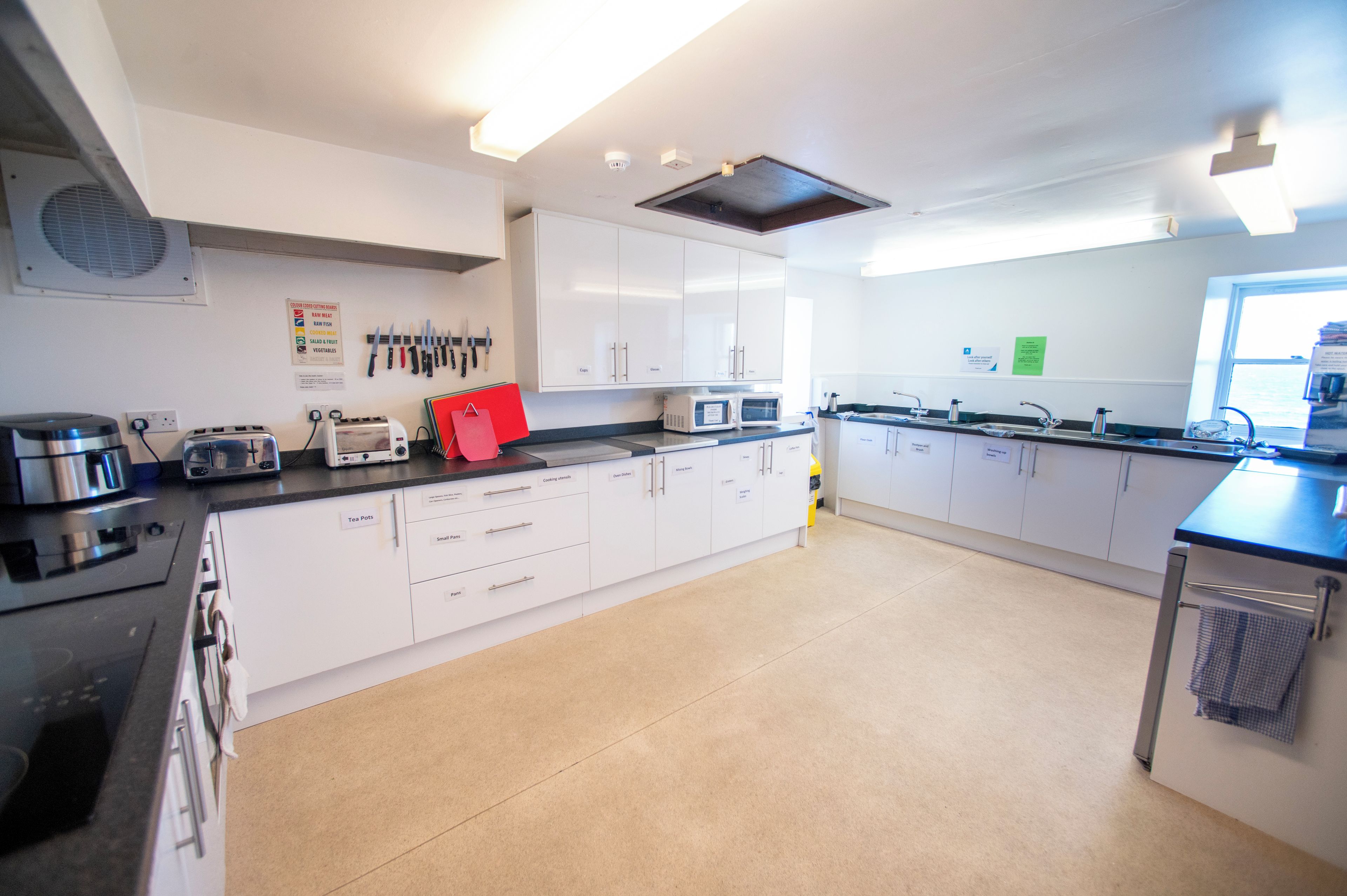 A modern kitchen with white cabinets, stainless steel appliances, and a large island with a sink and stove.