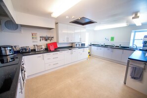 A modern kitchen with white cabinets, stainless steel appliances, and a large island with a sink and stove.