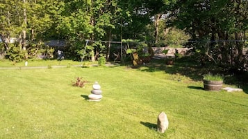 A grassy outdoor area with a stone structure and a potted plant.