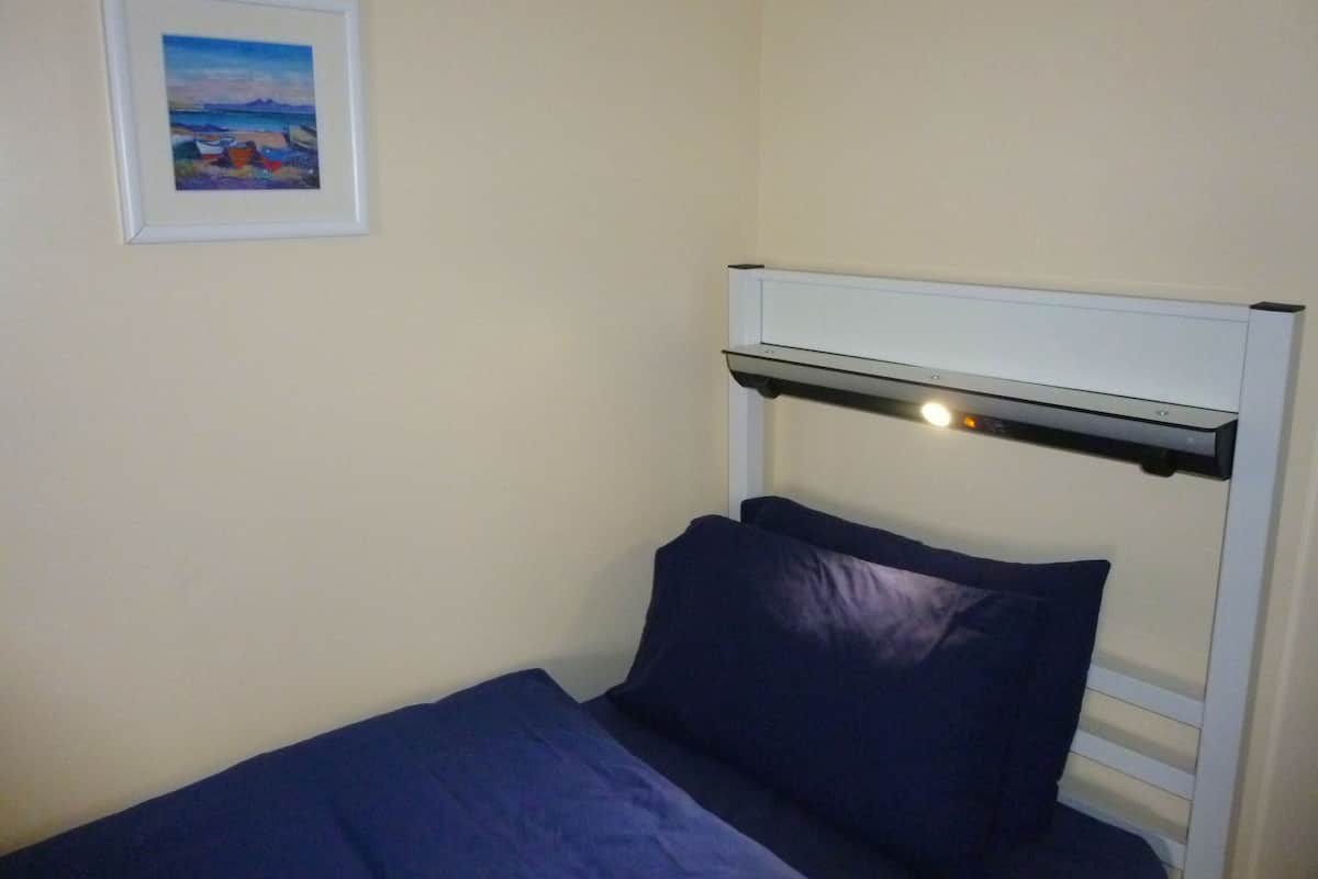 A single bed with a headboard and a framed picture on the wall.
