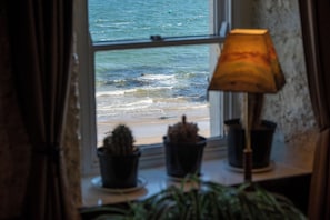 A window with a view of the sea, a lamp, and two potted plants on a windowsill. - Port Charlotte Youth Hostel (Islay Island)