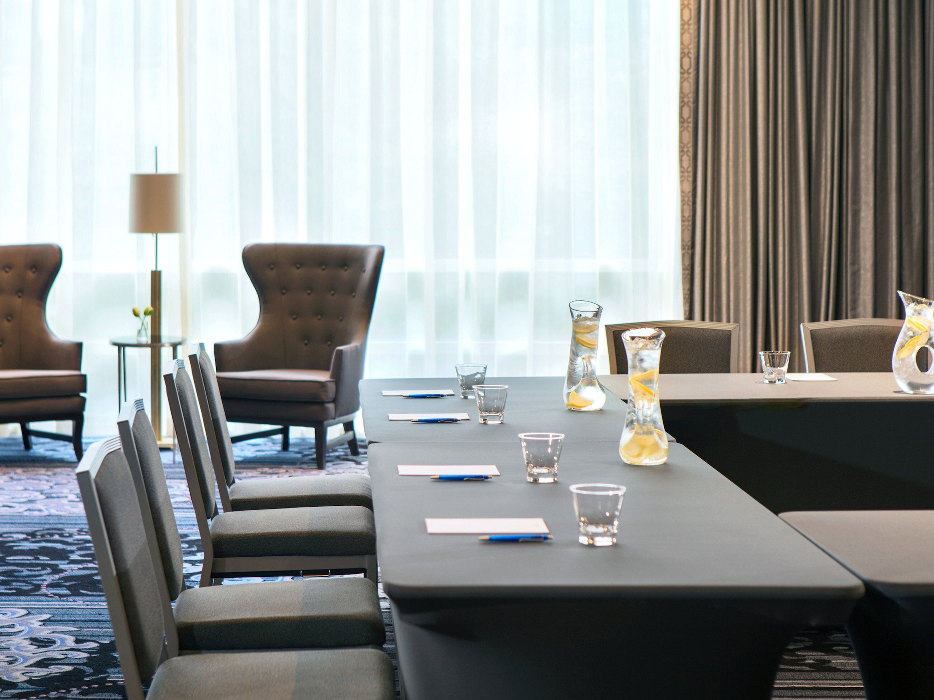 A conference room with a long table, chairs, and a vase with a lemon slice.