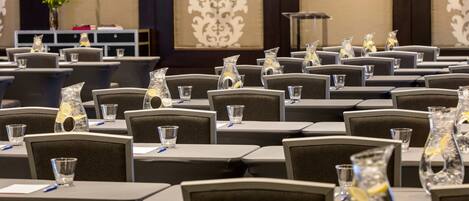 A conference room with tables set for meetings, equipped with water glasses and pens.