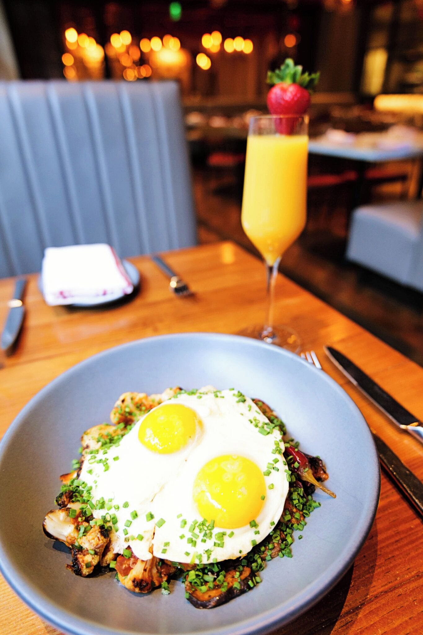 A plate of food with two sunny-side-up eggs, garnished with chives, on a blue plate.