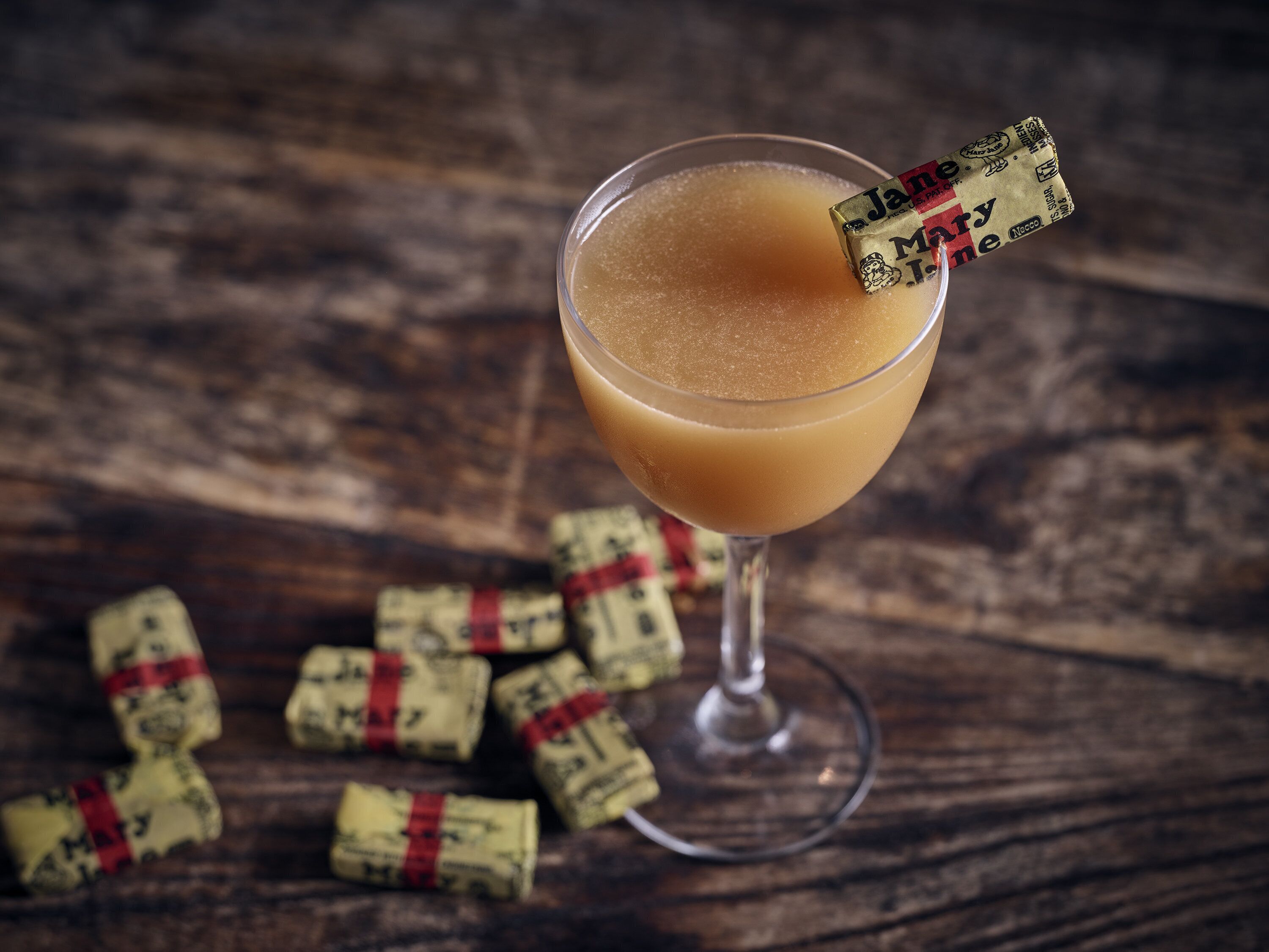 A cocktail in a glass with a straw, surrounded by corks on a wooden surface.