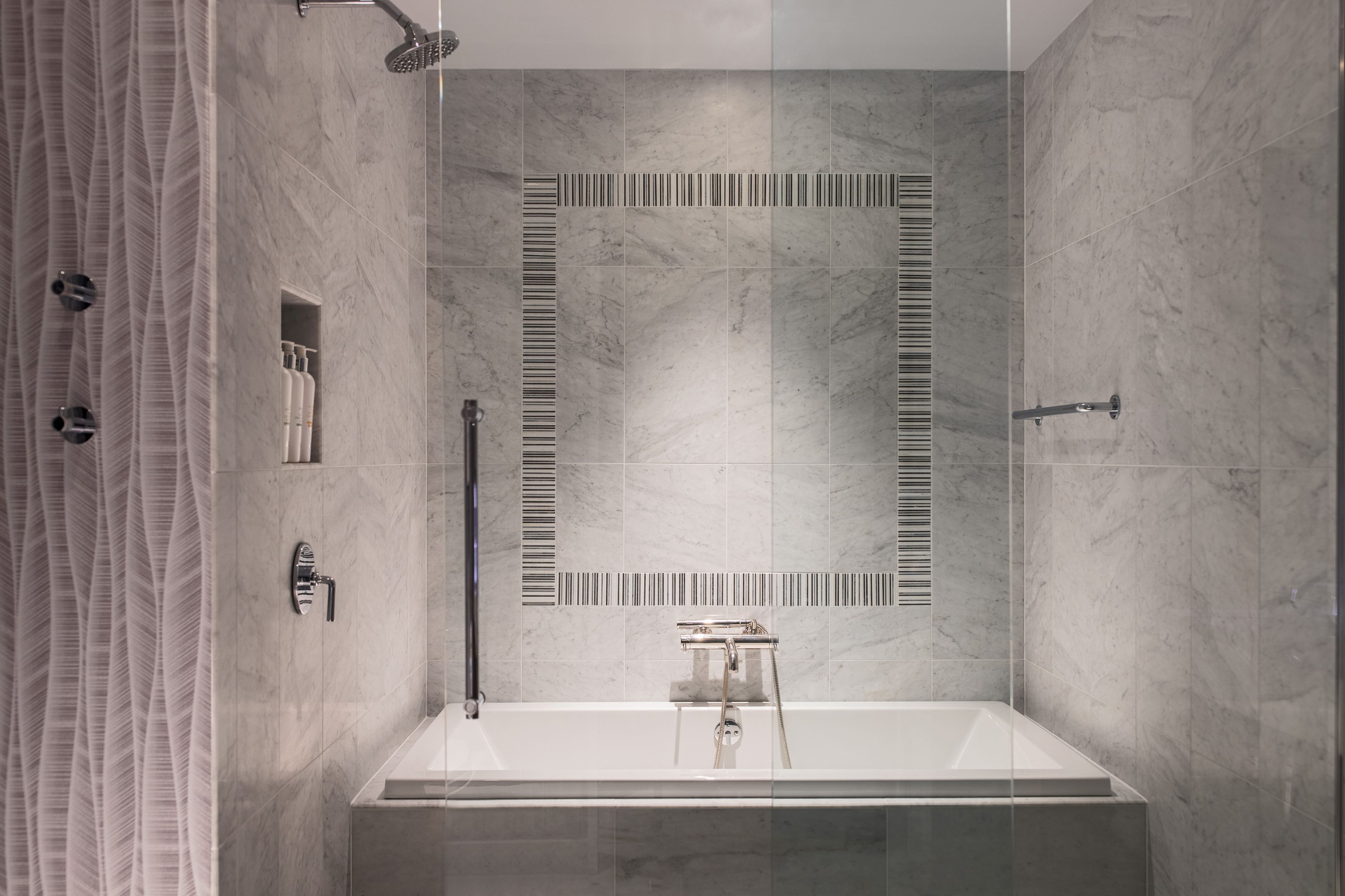 Un baño moderno con una bañera grande, un cabezal de ducha y un perchero para toallas.