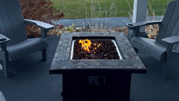 A patio area with two chairs, a fire pit, and a view of the water.
