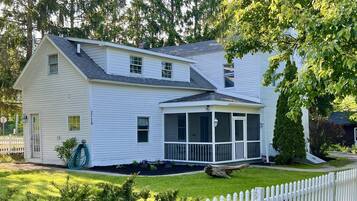 A two-story white house with a covered porch and a white picket fence.