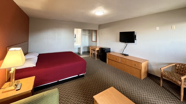 A hotel room with a bed, a desk, a TV, a chair, and a lamp. - Cotton Valley Motel (Clint)