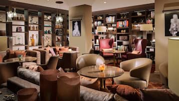 A modern lounge area with sofas, armchairs, and a bookshelf filled with books and decorative items.