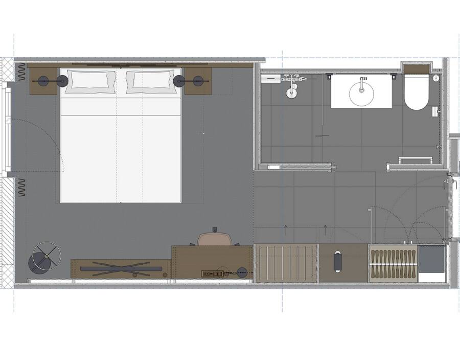 Ein Grundriss eines Hotelzimmers mit einem großen Bett, einem Schreibtisch, einem Sessel, einem kleinen Tisch, einer Sitzecke und einem Badezimmer mit Toilette und Waschbecken.