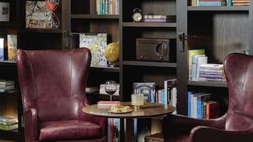 Eine Bibliothek mit Ledersesseln, einem Globus, Büchern und einem Vintage-Radio.