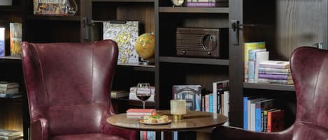 A library with leather chairs, a globe, books, and a vintage radio.