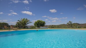 A clear blue swimming pool with lounge chairs and palm trees in the background. - Santa Clara Country Hotel (Odemira)