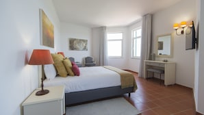 A bedroom with a bed, bedside table, lamp, and a desk with a chair. - Santa Clara Country Hotel (Odemira)