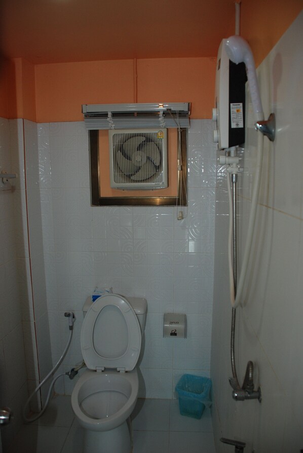 Un baño con inodoro, ducha y ventana con ventilador.