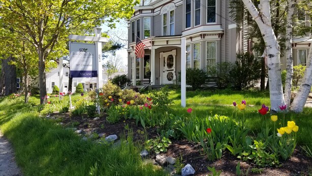 A historic house with a large front porch, a sign indicating a vacancy, and a well-maintained garden with tulips. - Blackberry Inn (Camden)