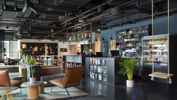 Uma área de bar moderna com assentos, balcão e prateleiras repletas de garrafas e copos.