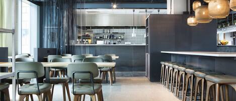 Un restaurant moderne doté d’un bar, d’un espace pour s’asseoir et d’une cuisine située à l’arrière-plan.