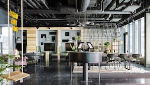 Espaço de escritório moderno com mesa central, área de estar e janelas amplas.
