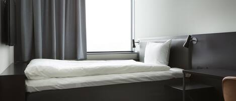 Una habitación de hotel moderna con una cama bien hecha, un escritorio y una silla.
