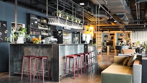 Uma área de bar moderna, com bancos, balcão e prateleiras repletas de garrafas e copos.