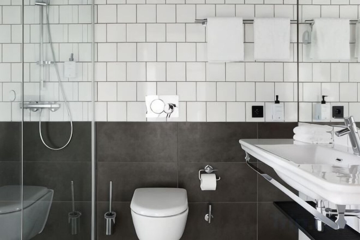 Un baño moderno con inodoro, bidé y zona de ducha con mampara de vidrio.