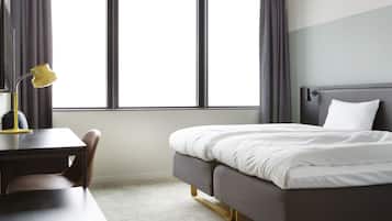 Habitación de hotel ordenada con una cama, un escritorio y una lámpara.