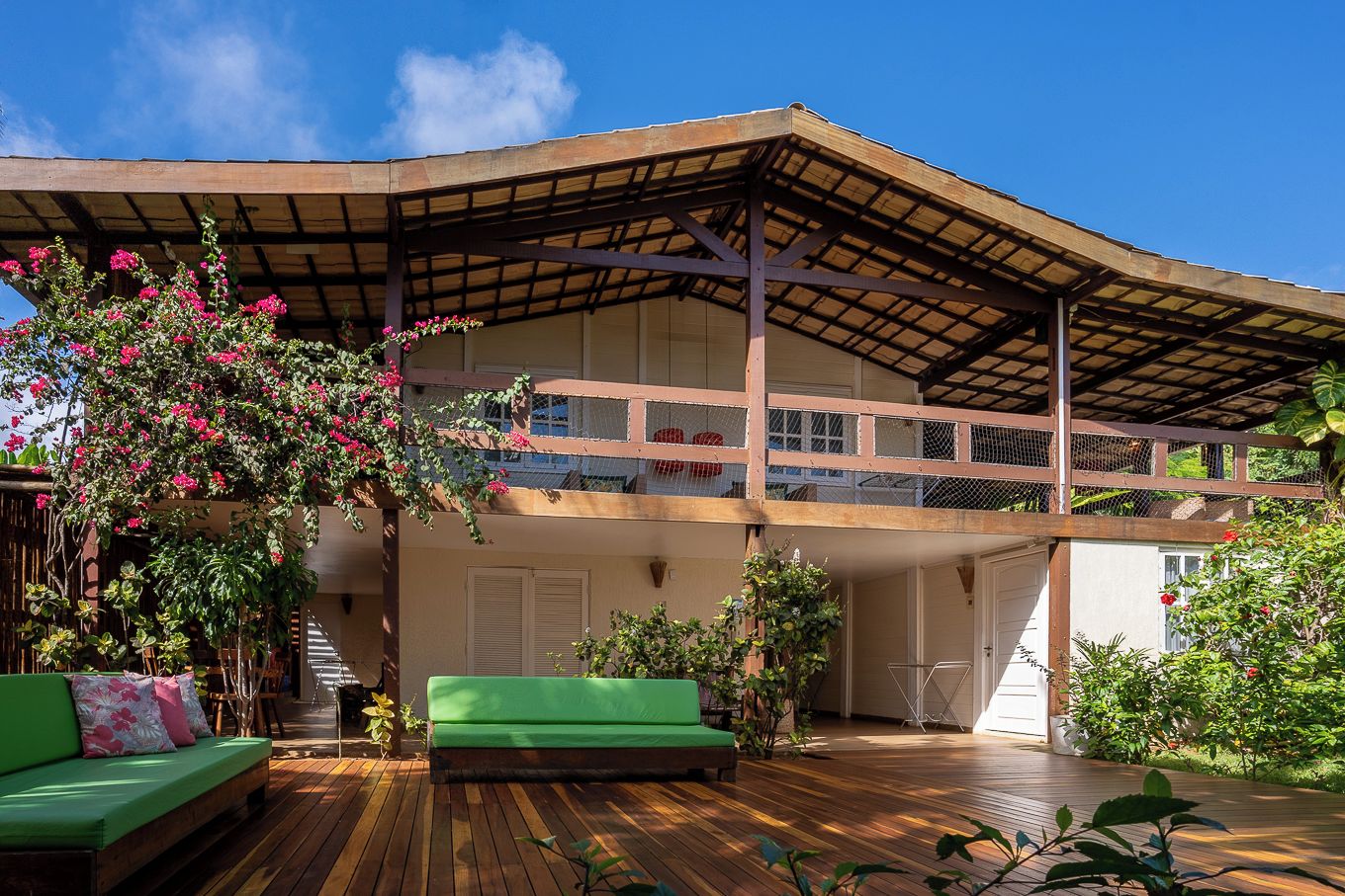 A two-story house with a wooden deck, a green sofa, and a covered outdoor area.