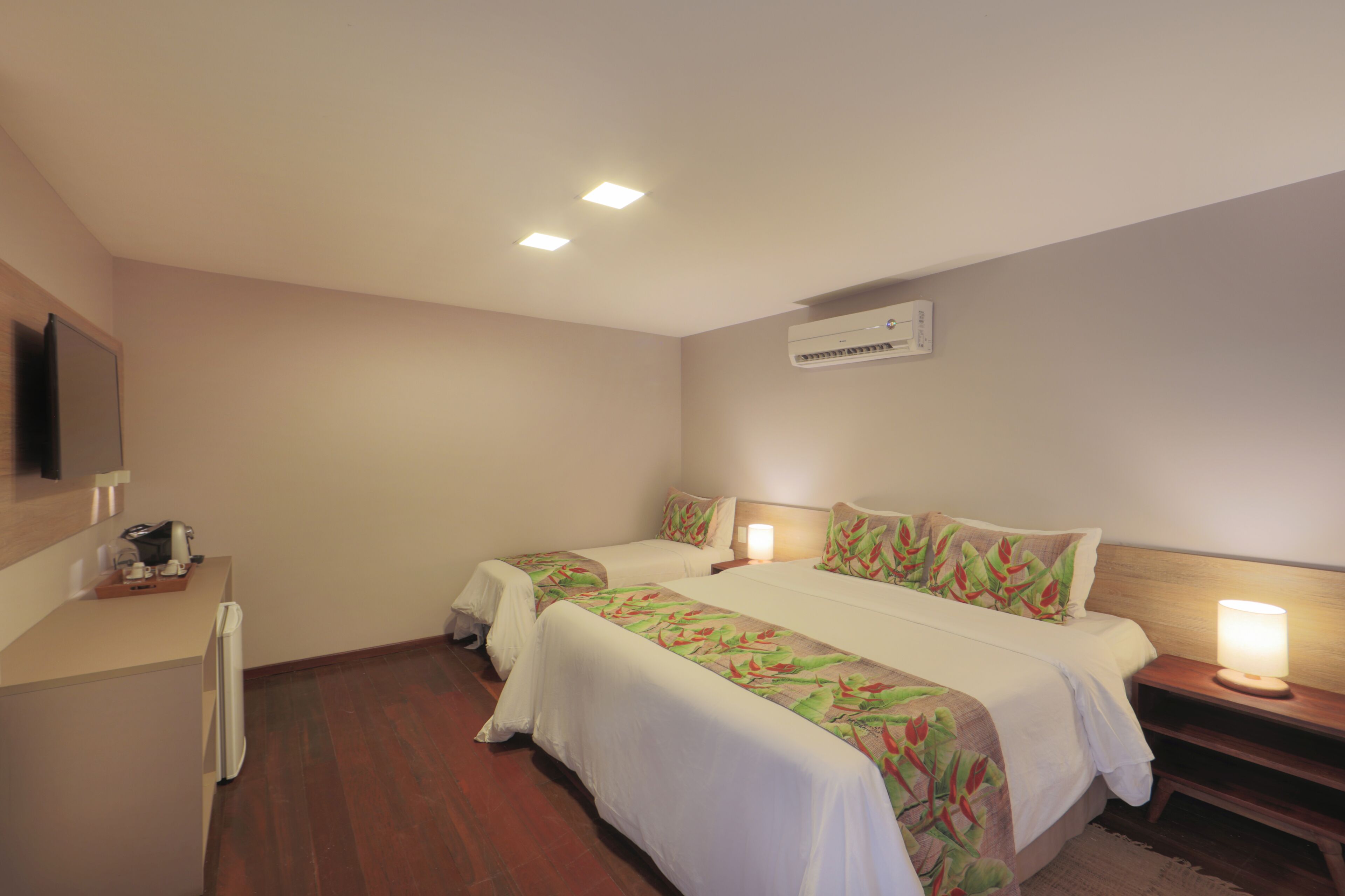 Quarto de hotel com duas camas, uma escrivaninha e televisão.