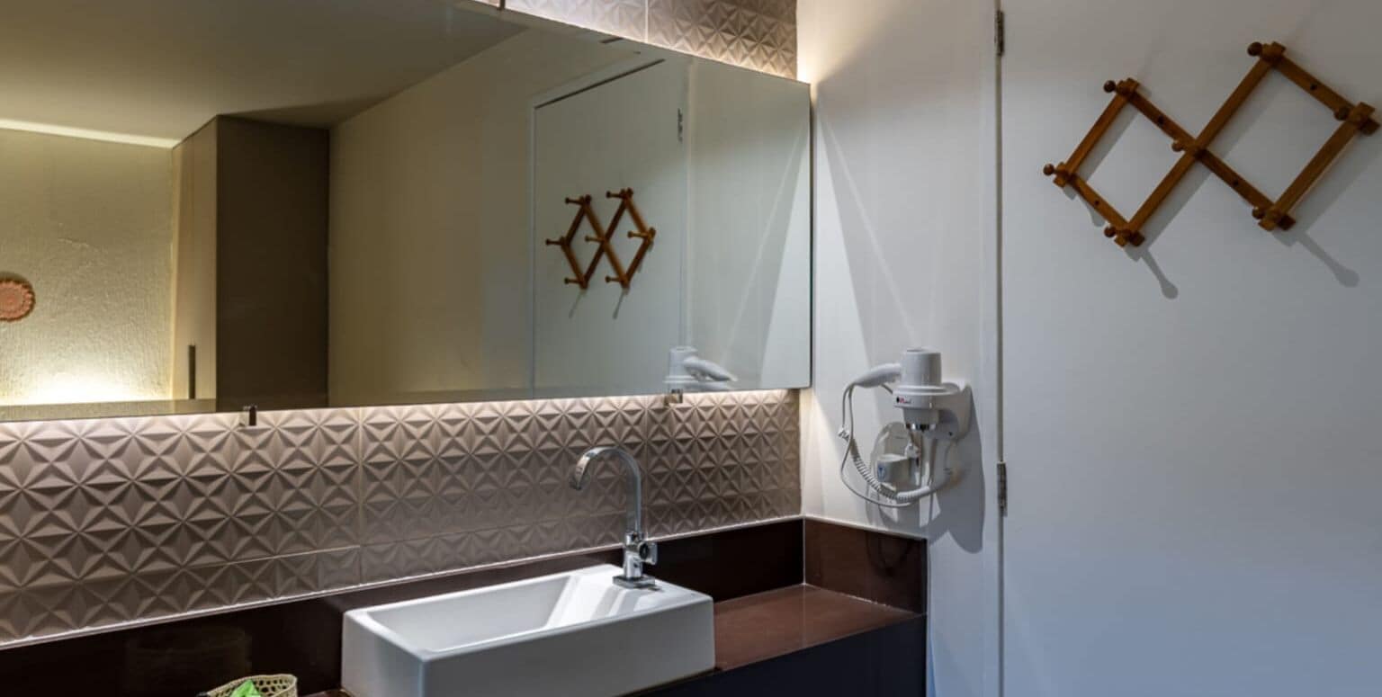 A modern bathroom with a rectangular sink, a large mirror, and a geometric patterned wall.