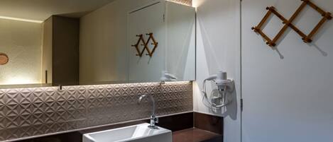 A modern bathroom with a rectangular sink, a large mirror, and a geometric patterned wall.