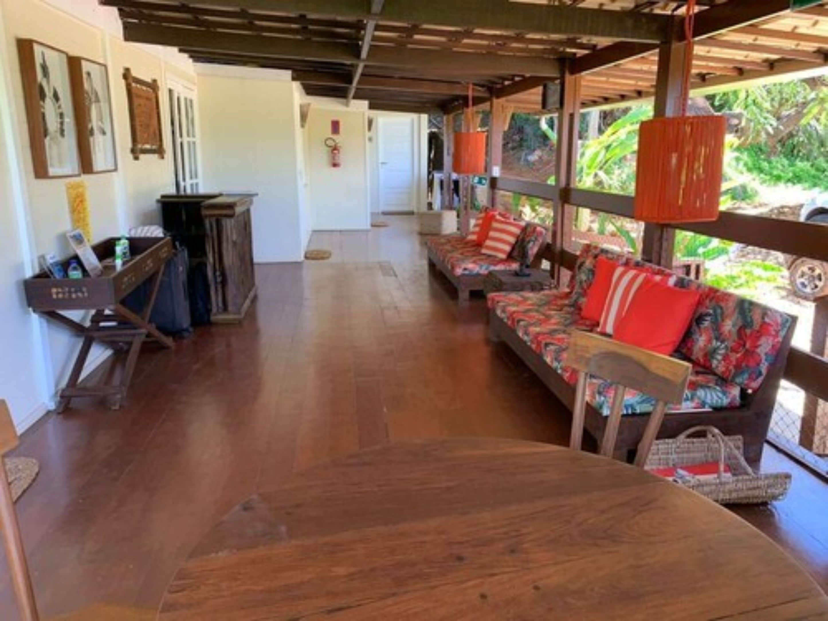 A covered outdoor seating area with wooden furniture and a fire extinguisher on the wall.