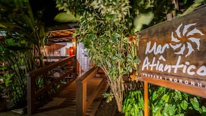 Une enseigne en bois portant les noms « Mar Atlantico » et « Pousada Noronha », indiquant un hôtel ou un établissement proposant des hébergements.