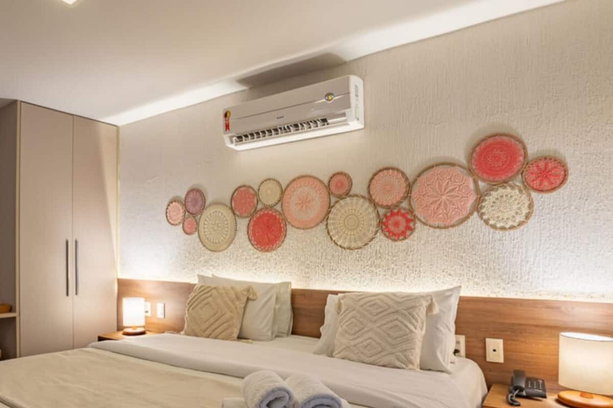 Ein Hotelzimmer mit Bett, Nachttischen, einem Heizkörper, einer Wand-Klimaanlage und einem Wandbild.