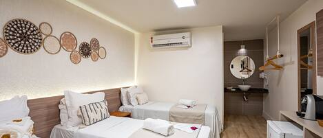 Habitación de hotel con dos camas, una mesita, un espejo, un lavamanos y un refrigerador.
