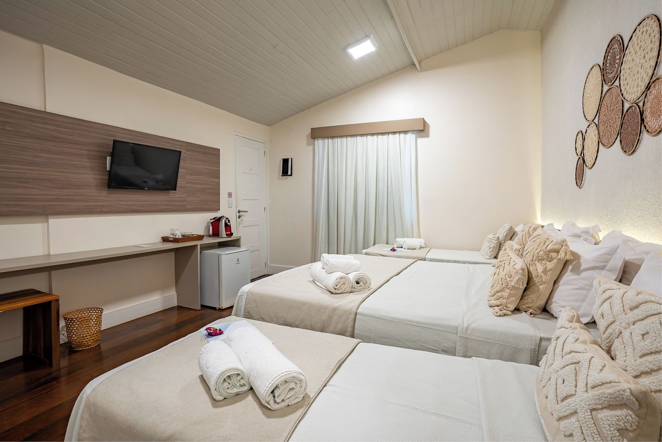 Une chambre d’hôtel avec deux lits, un téléviseur à écran plat, un bureau avec un ordinateur et une œuvre d’art accrochée au mur.