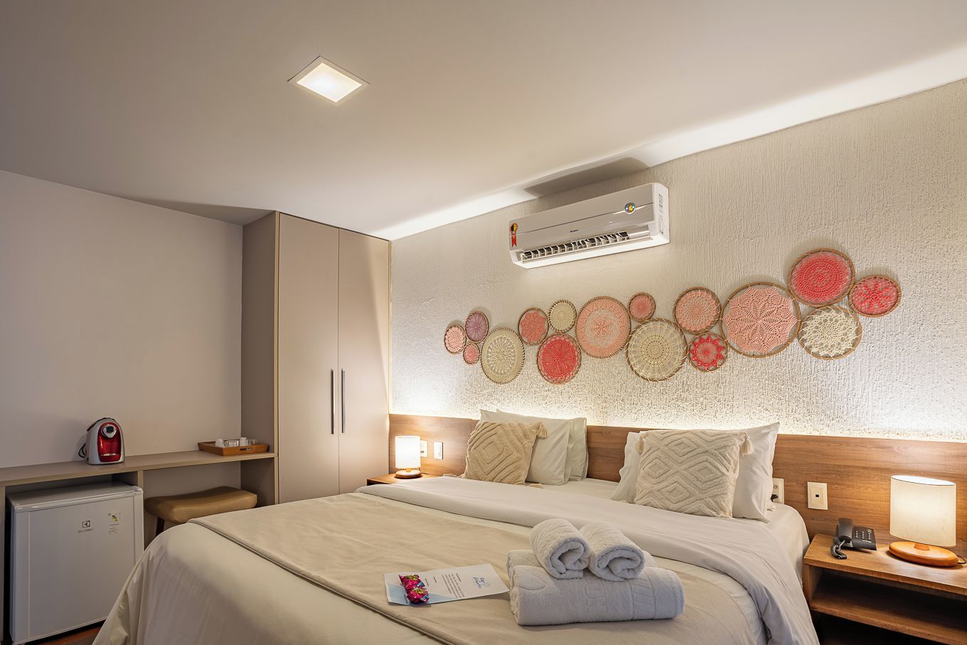Habitación de hotel con cama, mesitas de noche, aire acondicionado instalado en la pared y decoración en la pared.