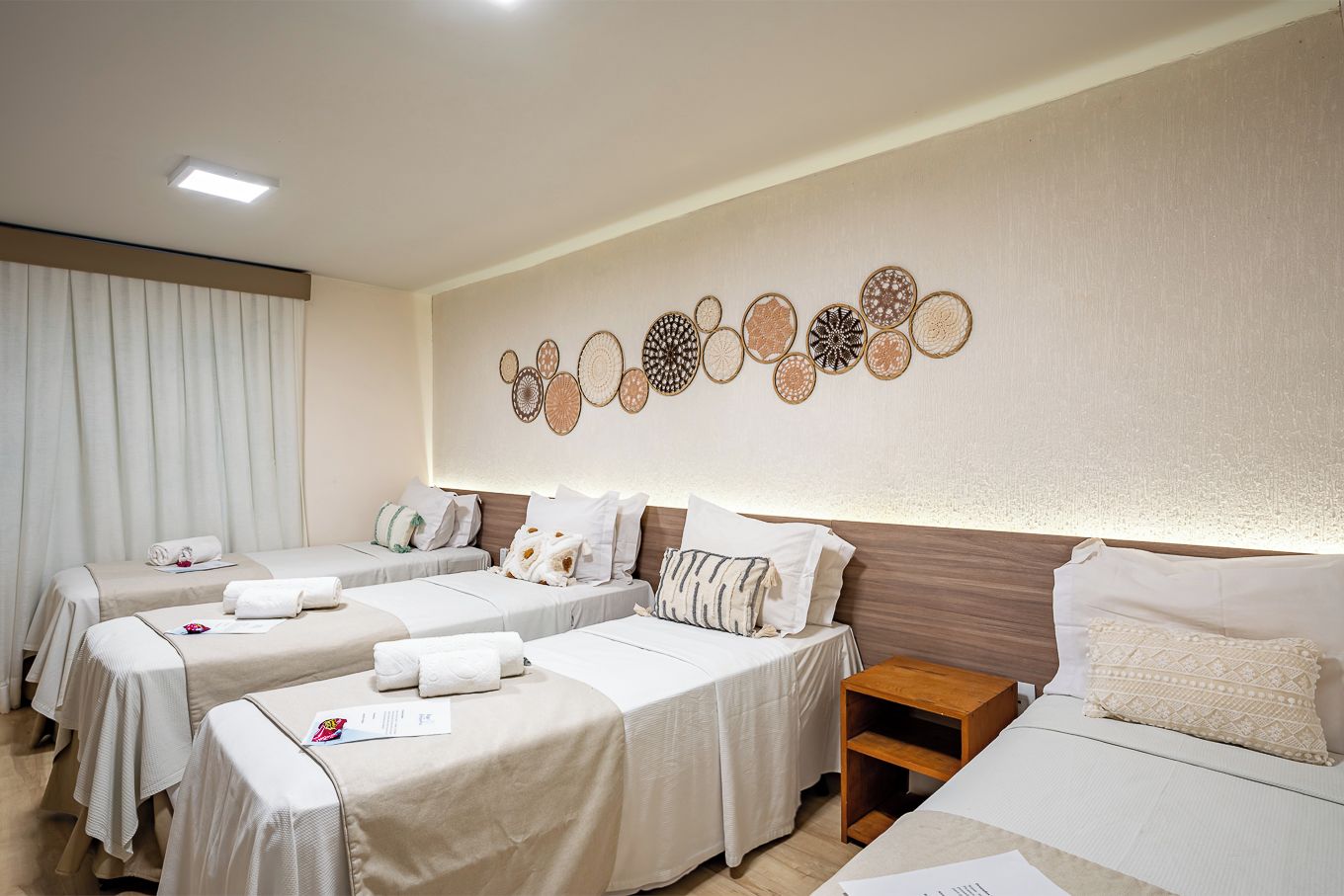 Una habitación de hotel con dos camas individuales, una mesita de noche de madera y una pared con diseños circulares decorativos.