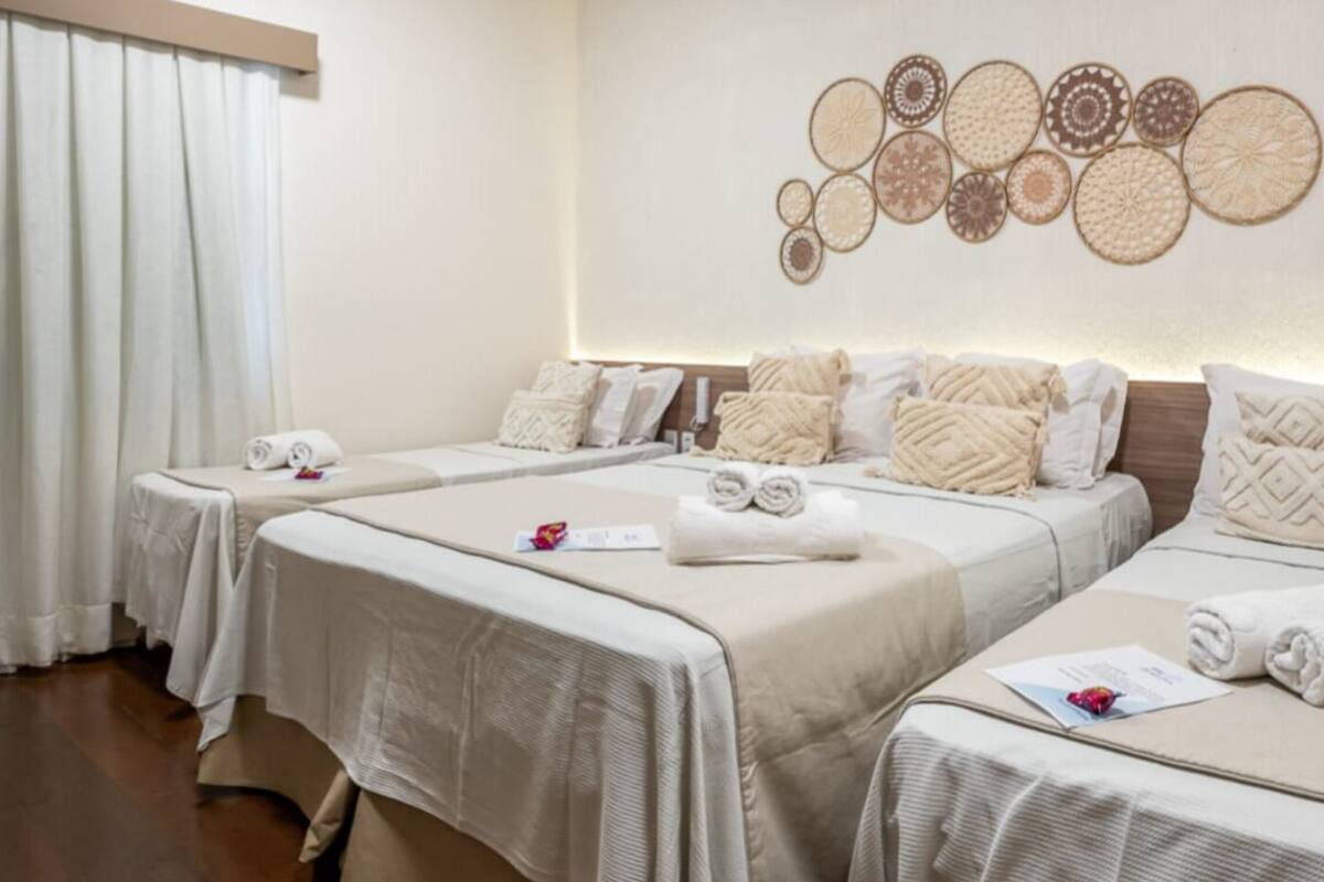 Ein Hotelzimmer mit zwei Betten, jeweils mit ordentlich gefaltetem Handtuch und Kissen.